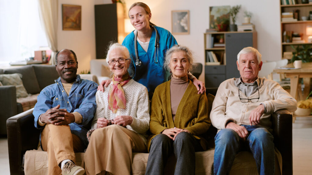 Idosos sentados no sofá de um lar a tirar foto com a cuidadora