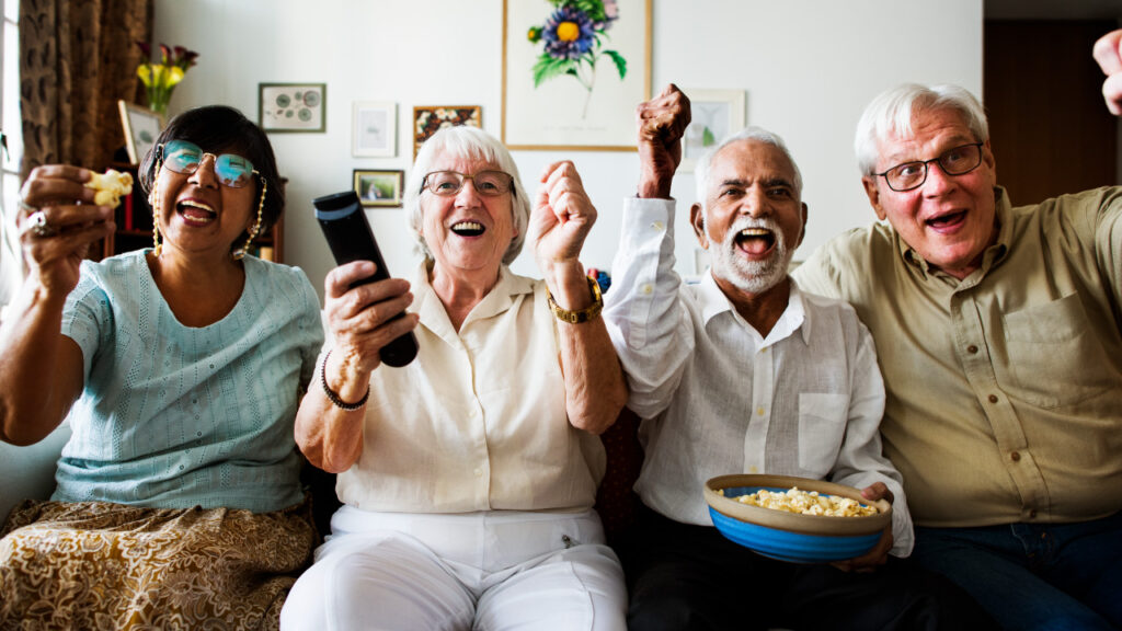 Grupo de idosos sentados no sofá felizes a ver um filme