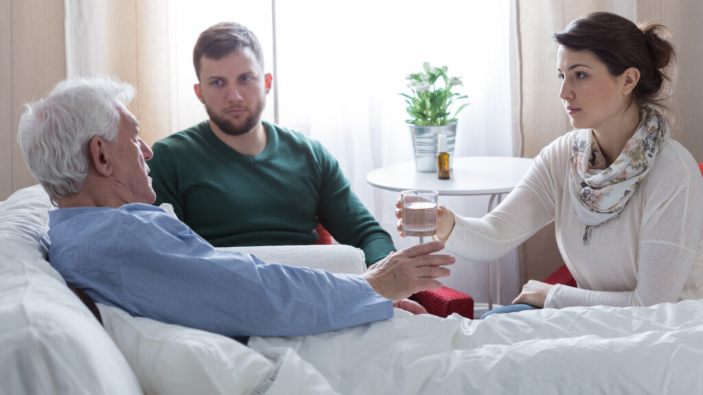 Idoso deitado na cama acompanhado dos seus familiares