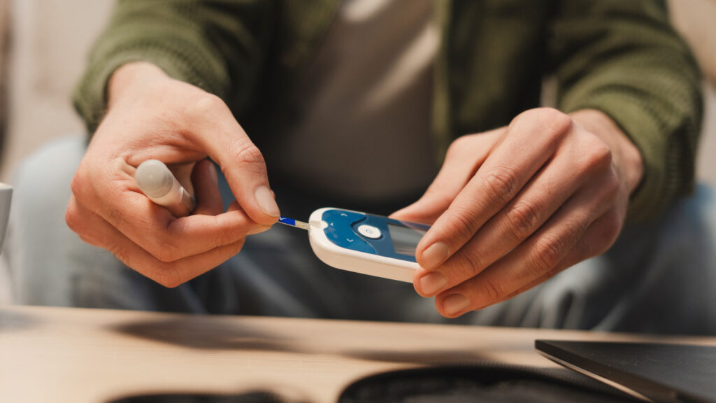 Senhor a realizar o teste do valor dos diabetes no aparelho