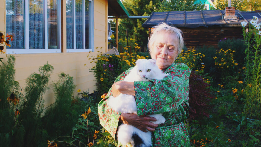 Senhora idosa no jardim da sua casa com um gato ao colo