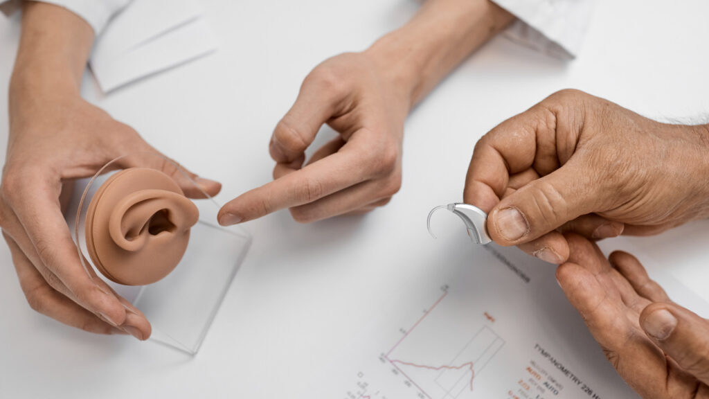 mãos da médica a agarrar no aparelho e a explicar ao idoso como funciona