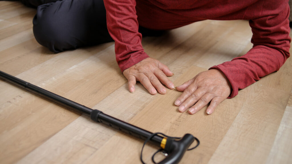 Idoso caído no chão com uma bengala ao lado