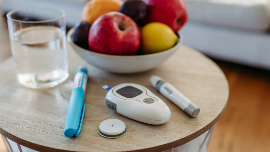 Mesa com uma taça de fruta, insulina e aparelhos de medição de diabetes