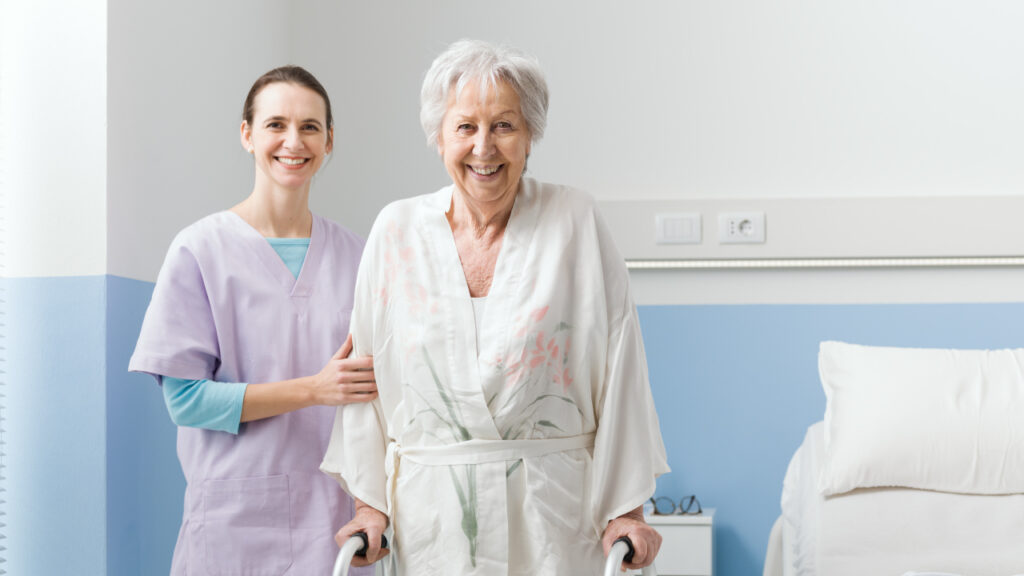 Senhora idosa, feliz, a ser acompanhada pela enfermeira